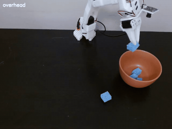 The arm pulls a far sponge closer with the closed gripper, then picks it up